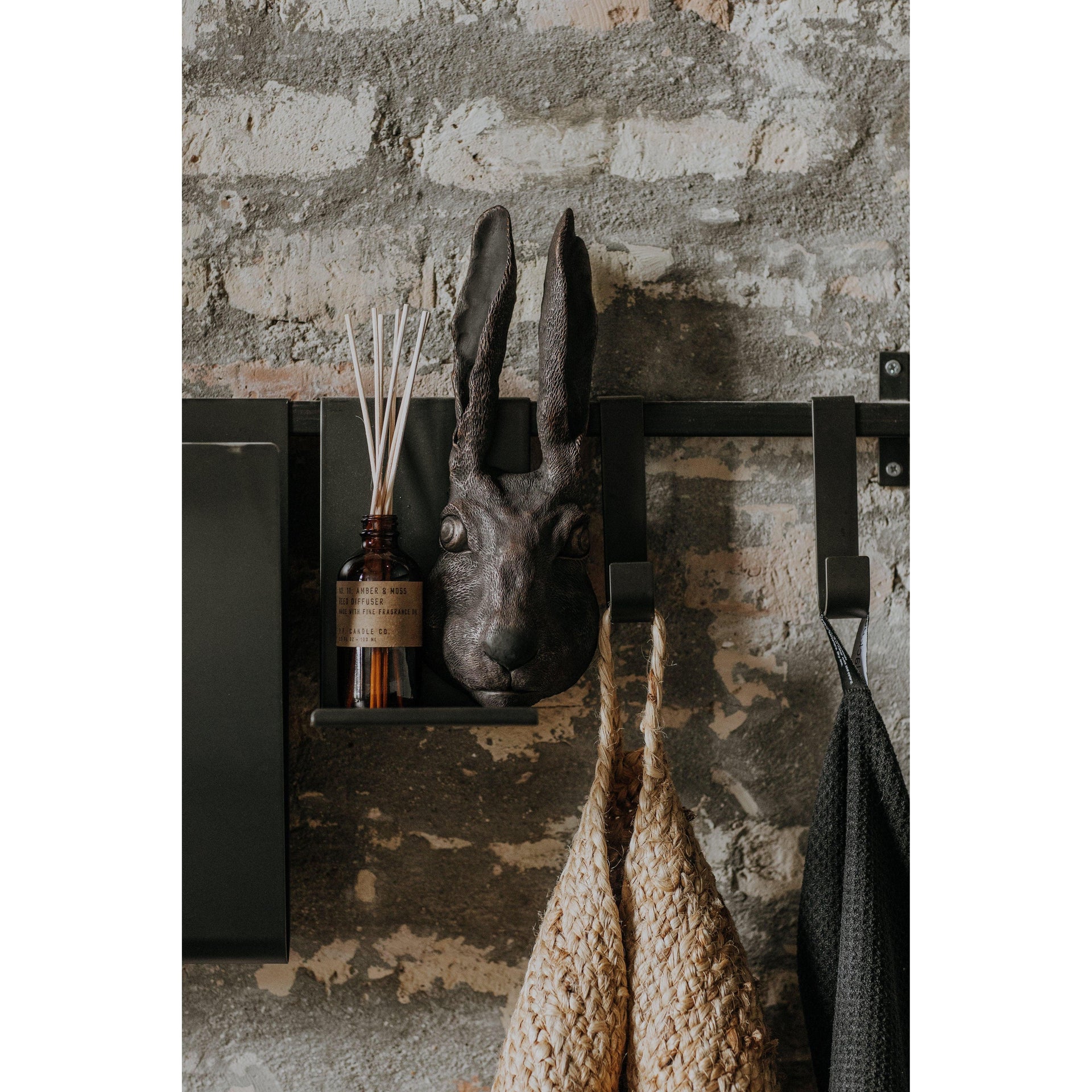 Decorative rabbit head mounted on a stone wall with a diffuser and basket below.
